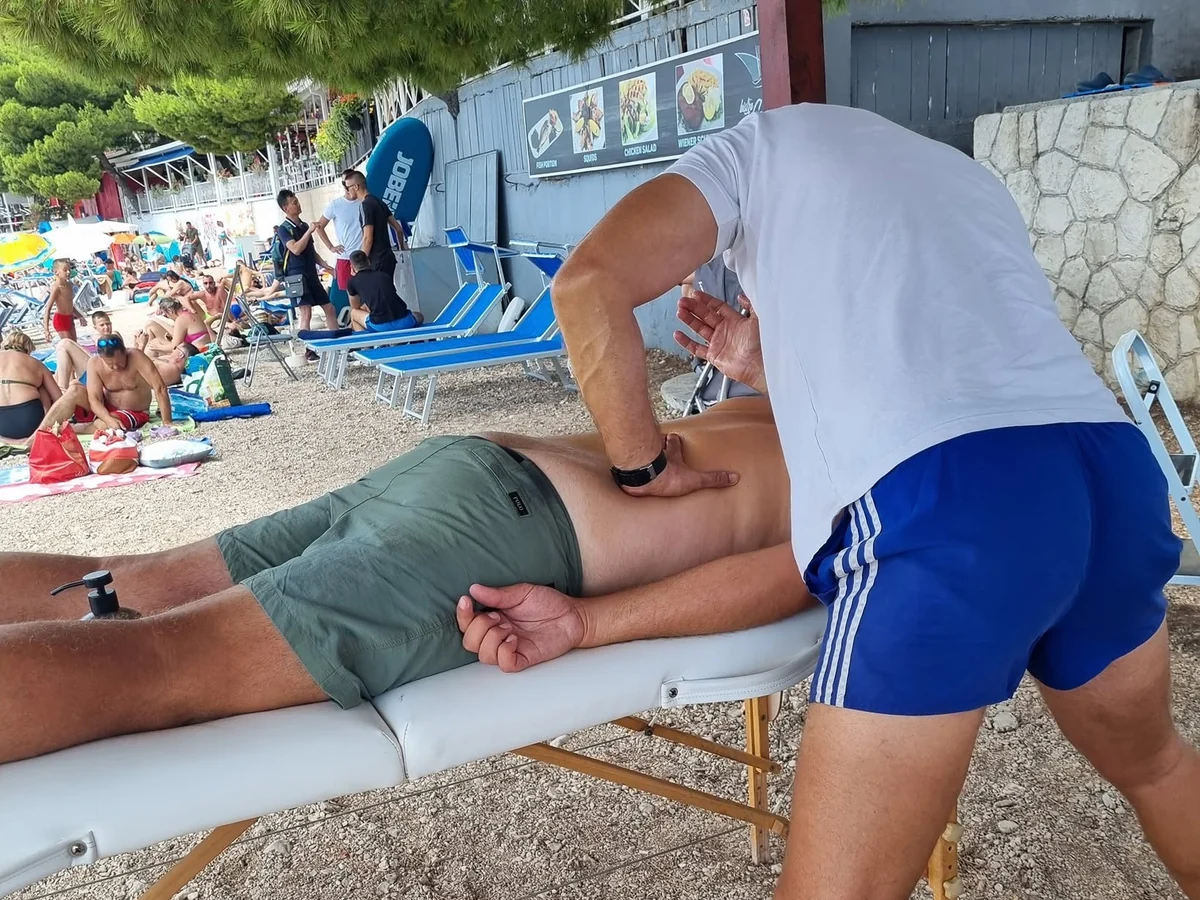An individual manual treatment for a guest on a massage table beside the beach in Makarska.